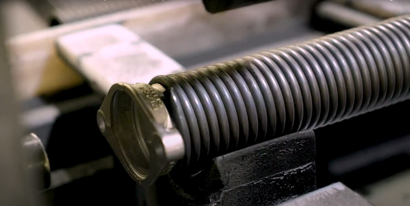 A skilled technician from Bee Ridge Garage Door Repair inspecting a garage door spring for repair.