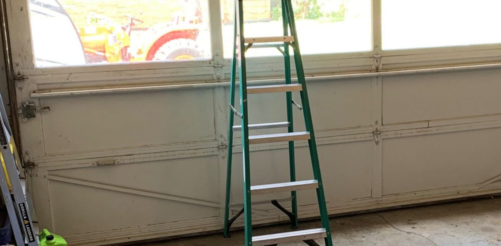 a skilled technician from Bee Ridge Garage Door Repair performing maintenance and adjustments on a residential garage door with a set of tools, demonstrating expert garage door repair services.